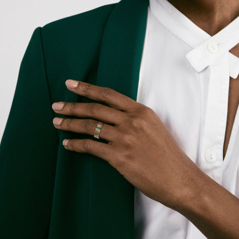 Wide architectural gold ring with green baguette stone worn on hand