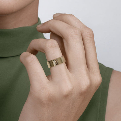 Flat gold band with exposed grey brown baguette stone shown worn in natural light