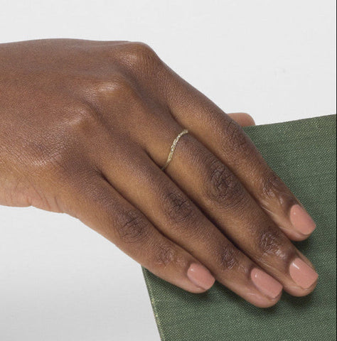 Thin knife edge wedding band with pavé diamonds worn on hand