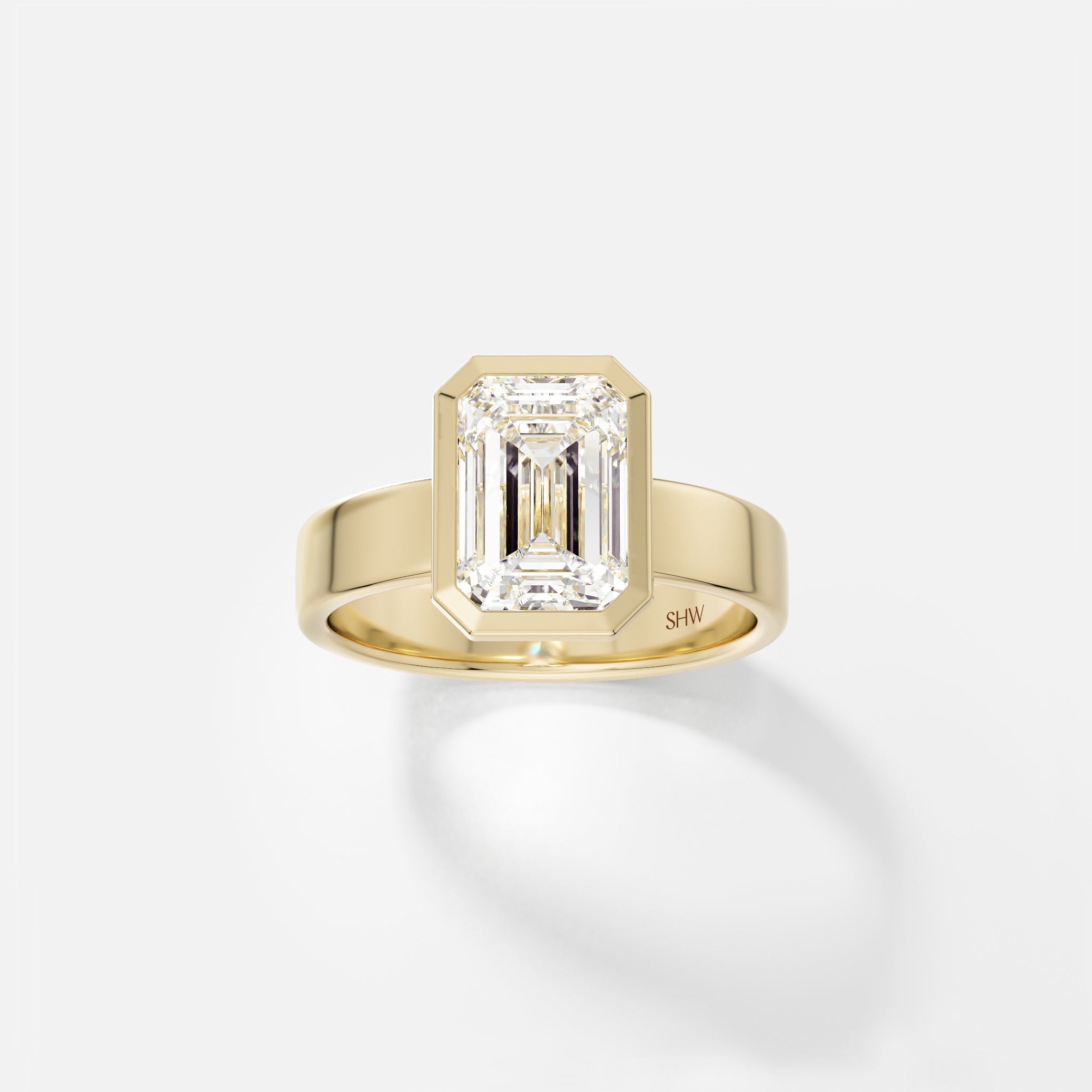 14k yellow gold wide flat band engagement ring with 2.50 carat emerald-cut diamond in thin bezel setting