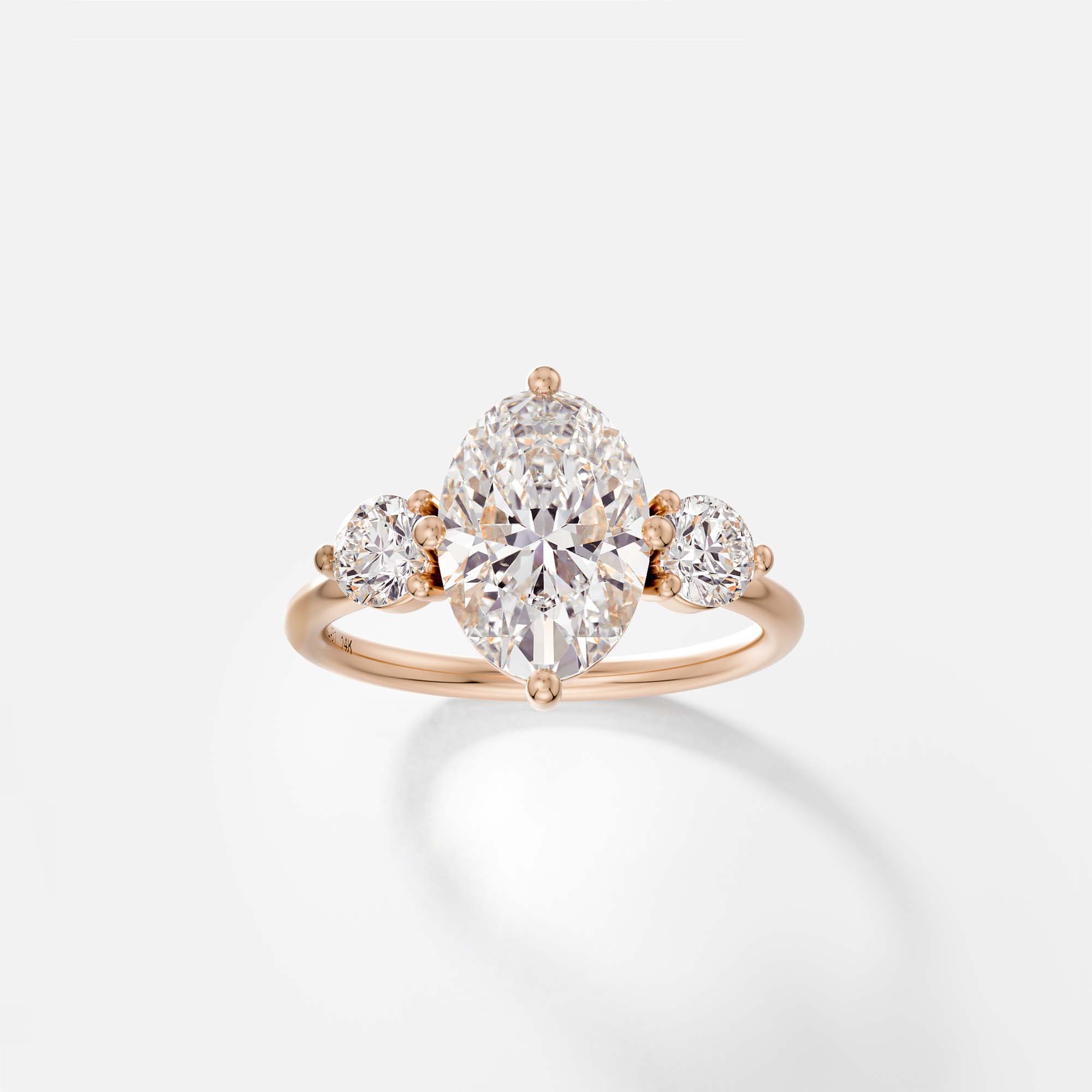 14k rose gold engagement ring with 2.50 carat oval diamond and round side stones in prong setting