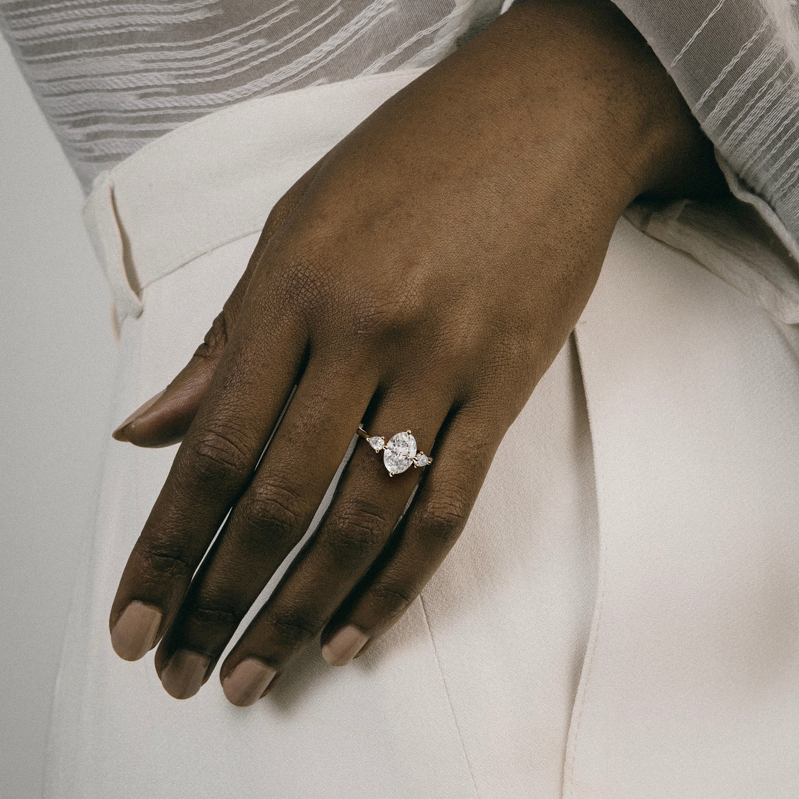 2 carat oval diamond three stone engagement ring with pear side stones worn on hand