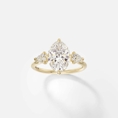 Kele oval diamond three stone engagement ring with pear side stones front view in 14k yellow gold