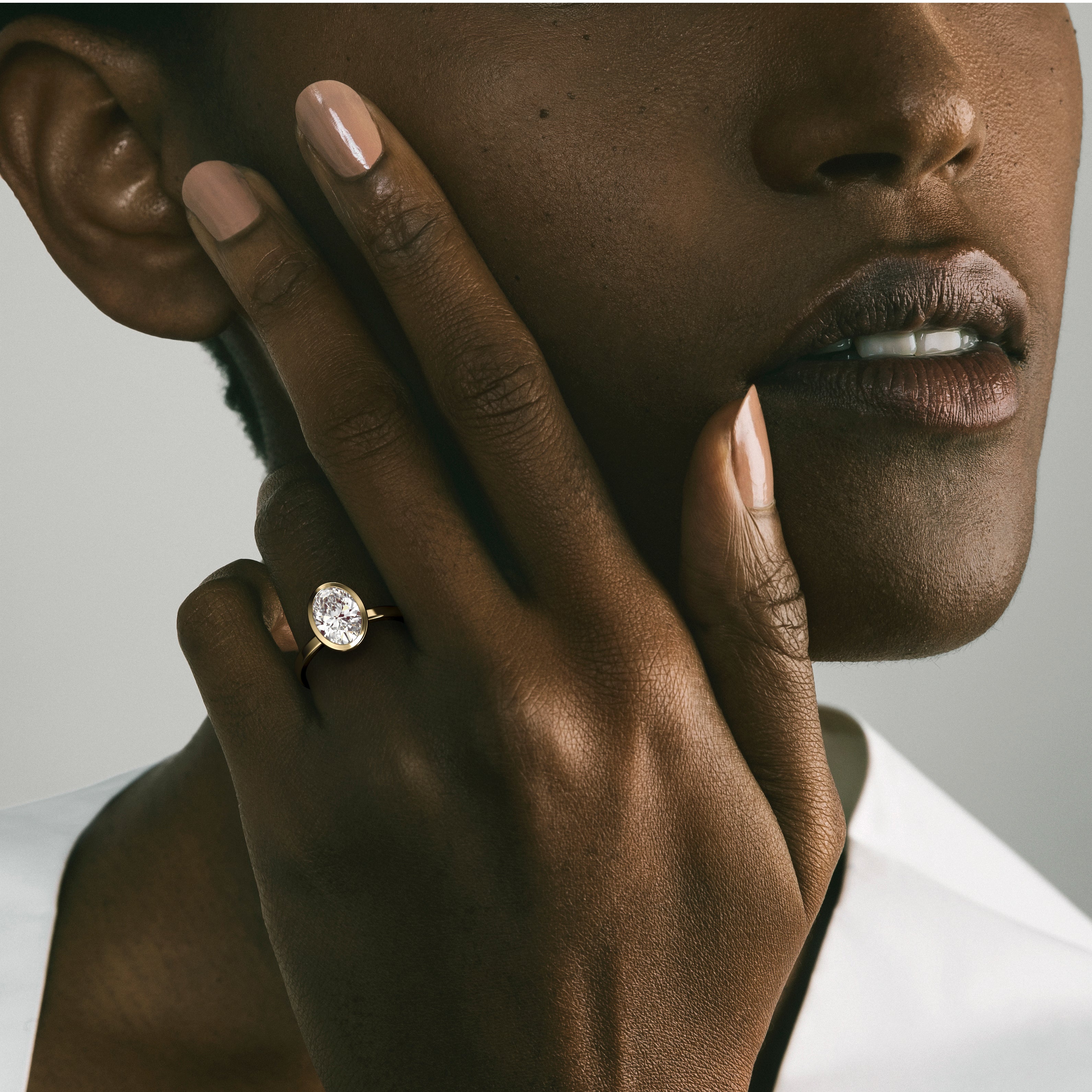 Minimal yellow gold engagement ring with bezel set oval diamond worn on hand