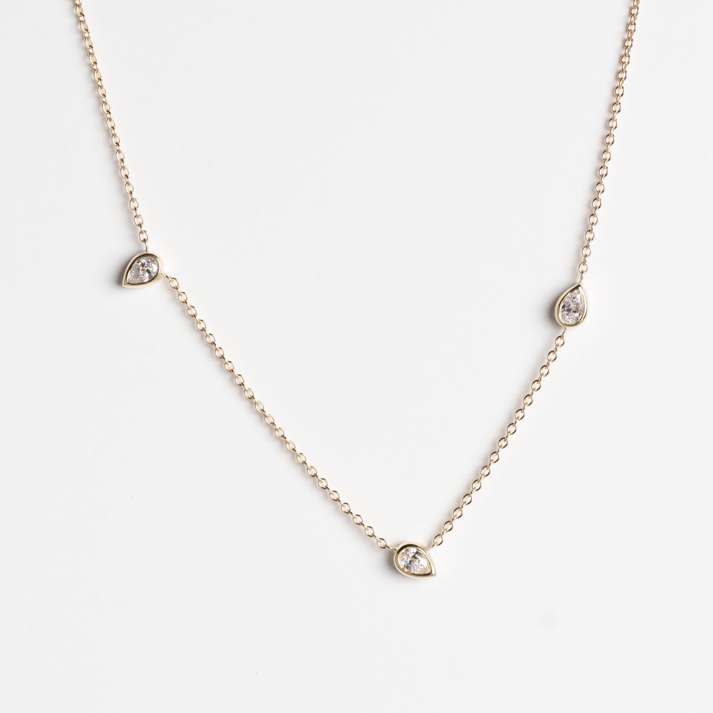 A delicate gold chain necklace featuring three small teardrop-shaped gold pendants, each set with white lab-grown diamonds, displayed against a clean white background.