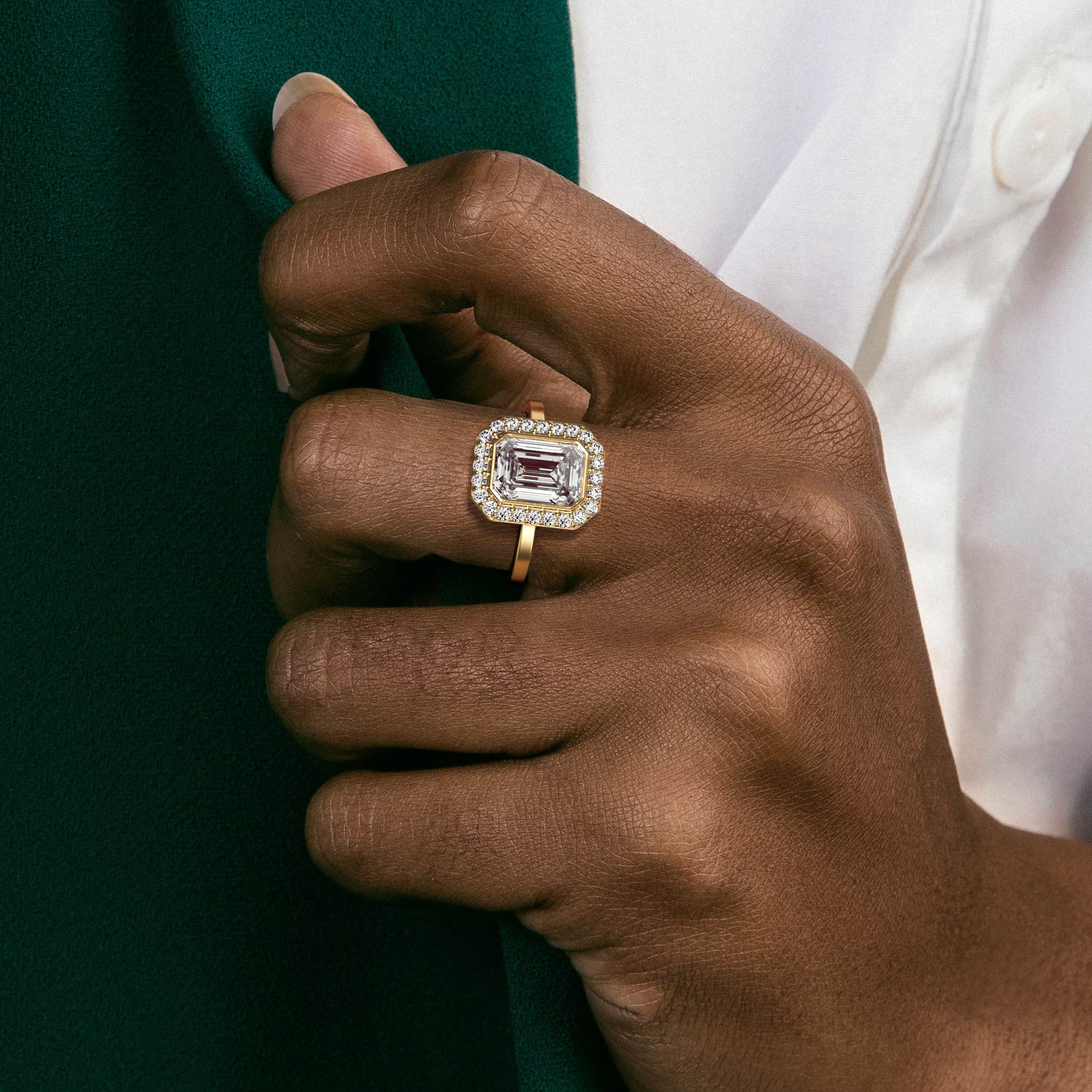 Close view of emerald-cut diamond halo engagement ring with pavé halo on flat band