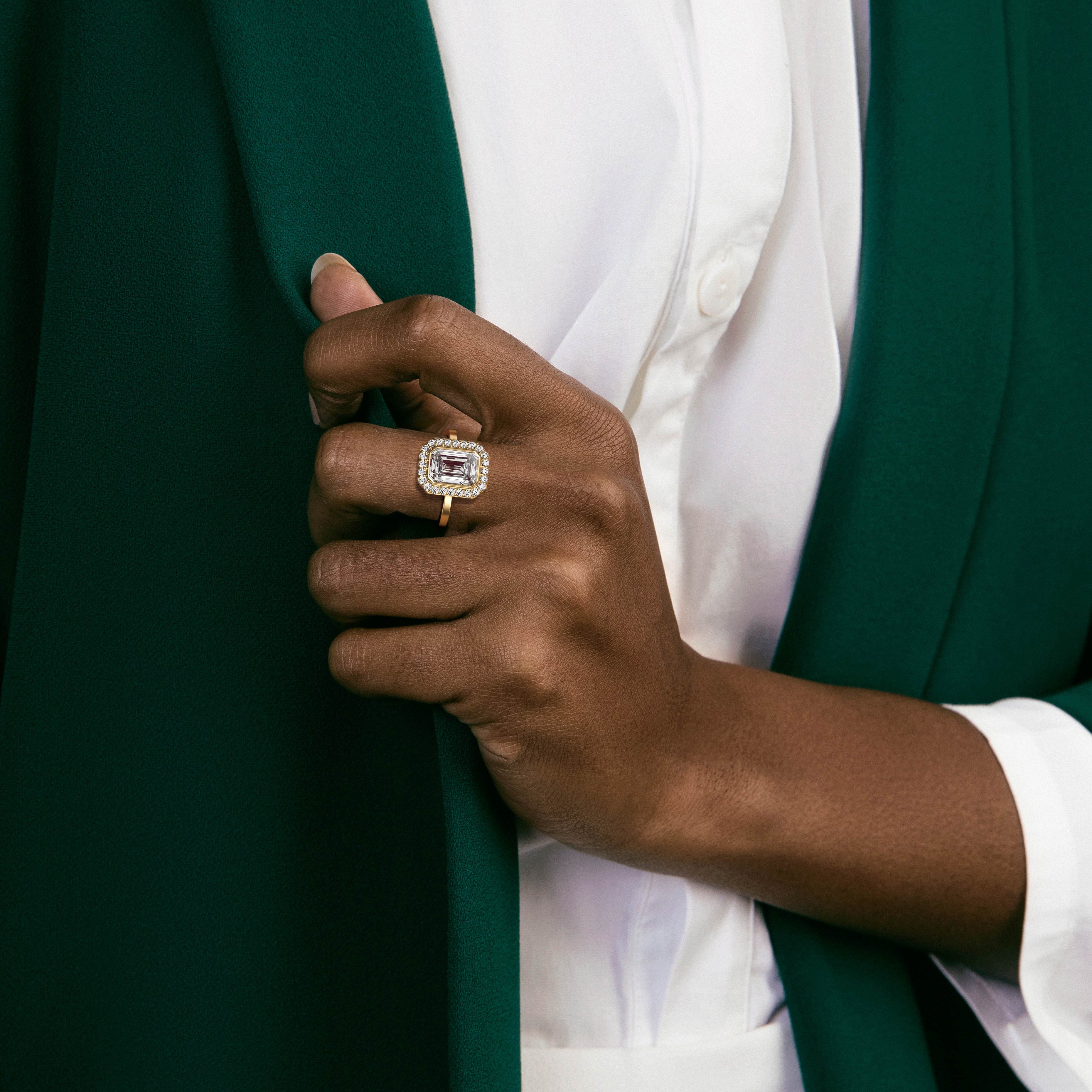 14k yellow gold halo engagement ring with emerald-cut diamond worn on hand