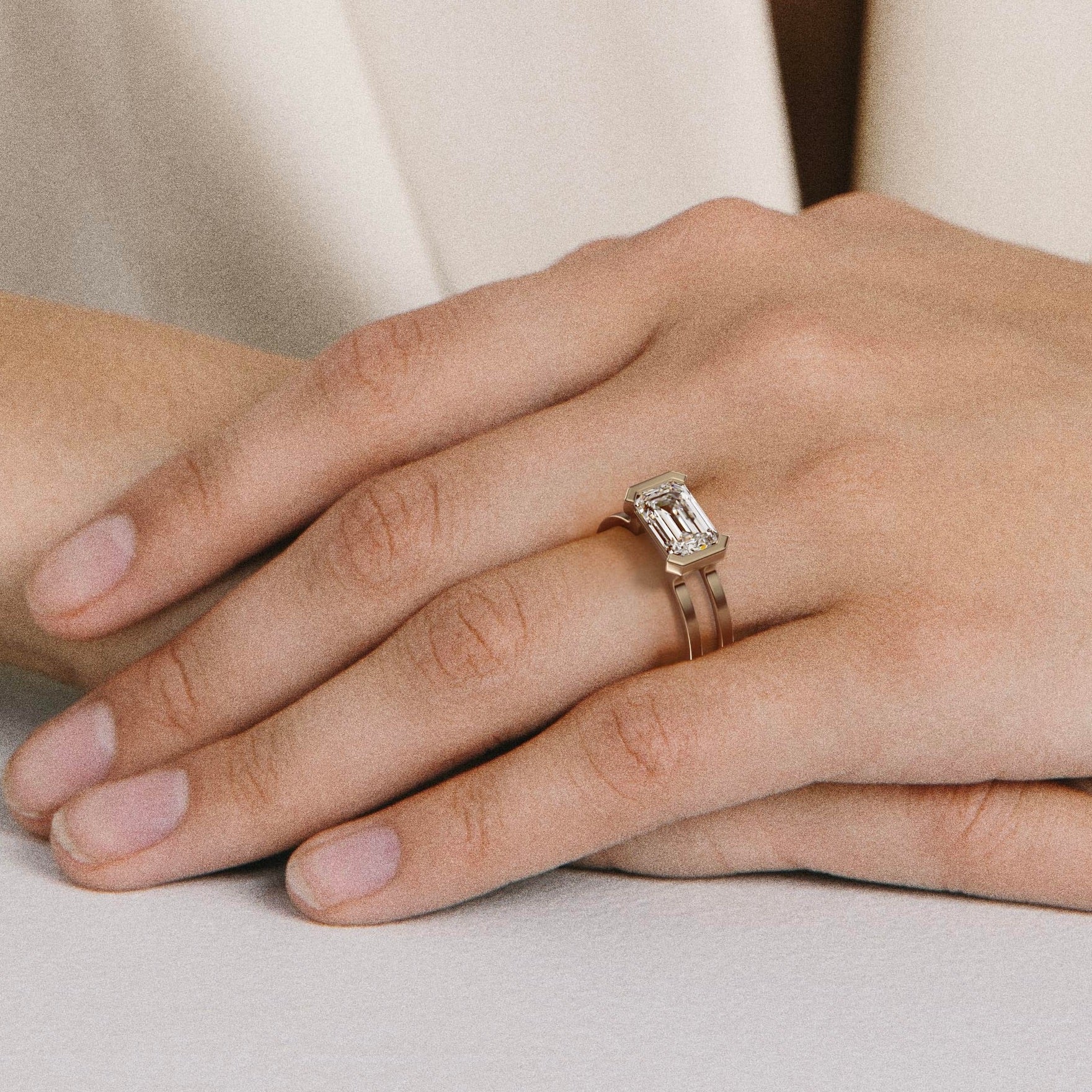 close view of east-west emerald diamond engagement ring with double band and partial bezel