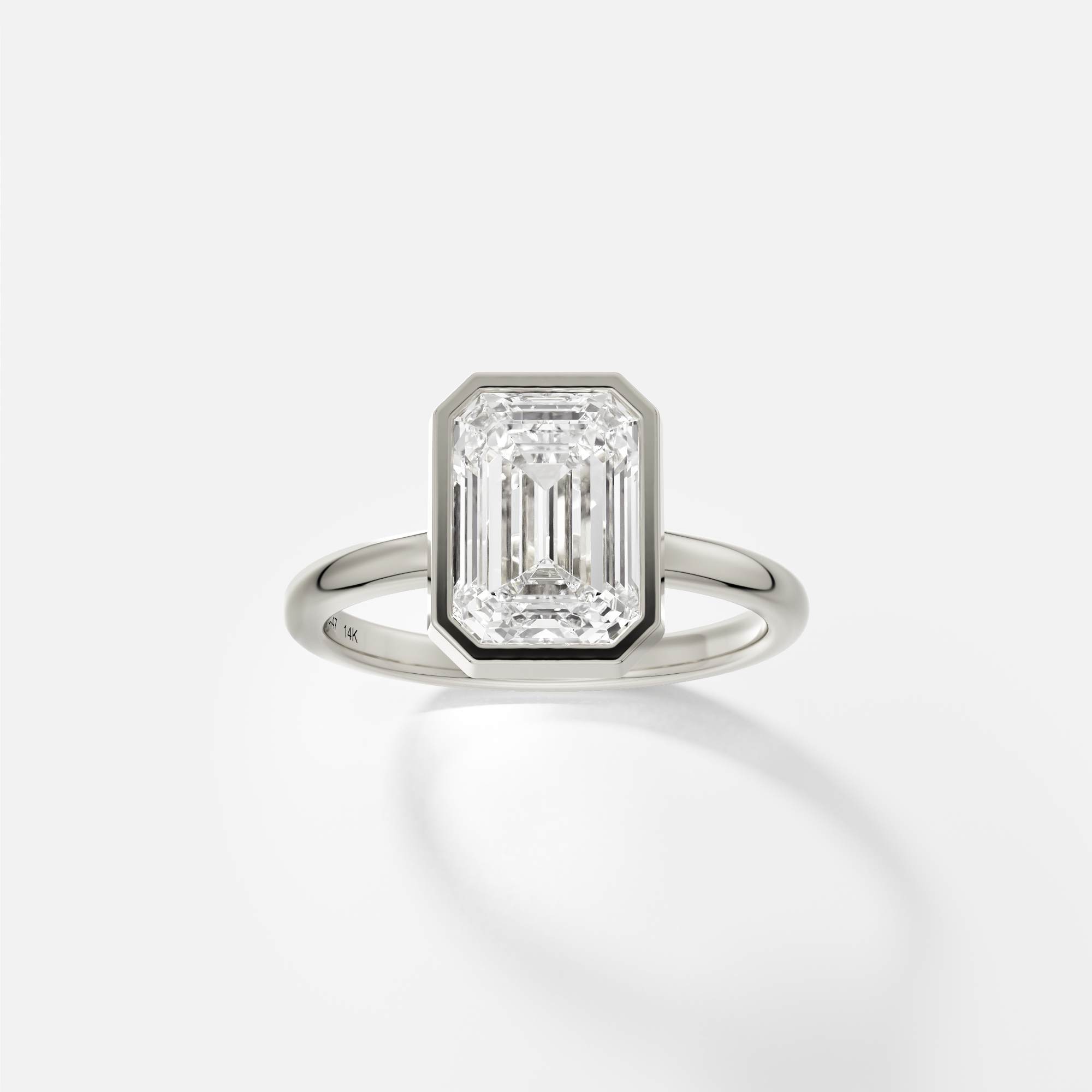 14k white gold engagement ring with 2.50 ct emerald-cut diamond in thin bezel setting on domed band
