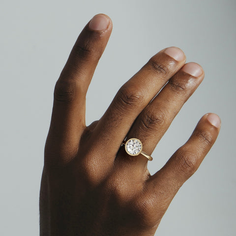 Syd round brilliant diamond bezel engagement ring worn on hand