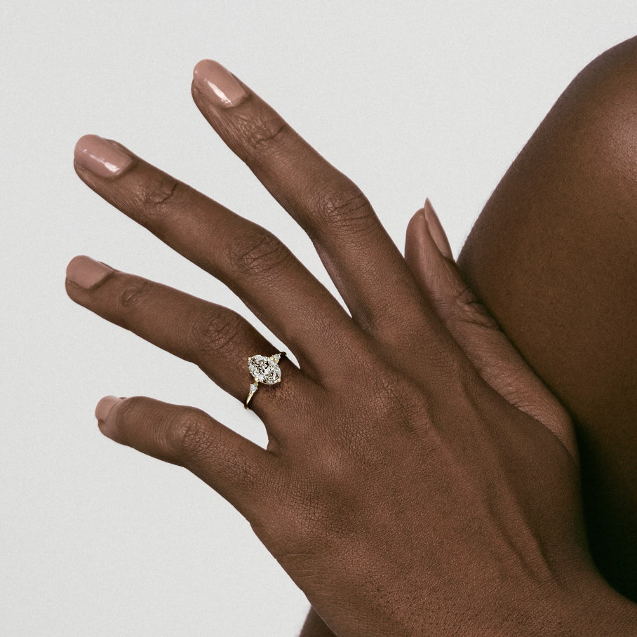 Close view of three stone engagement ring with oval diamond and pear accent stones on delicate band