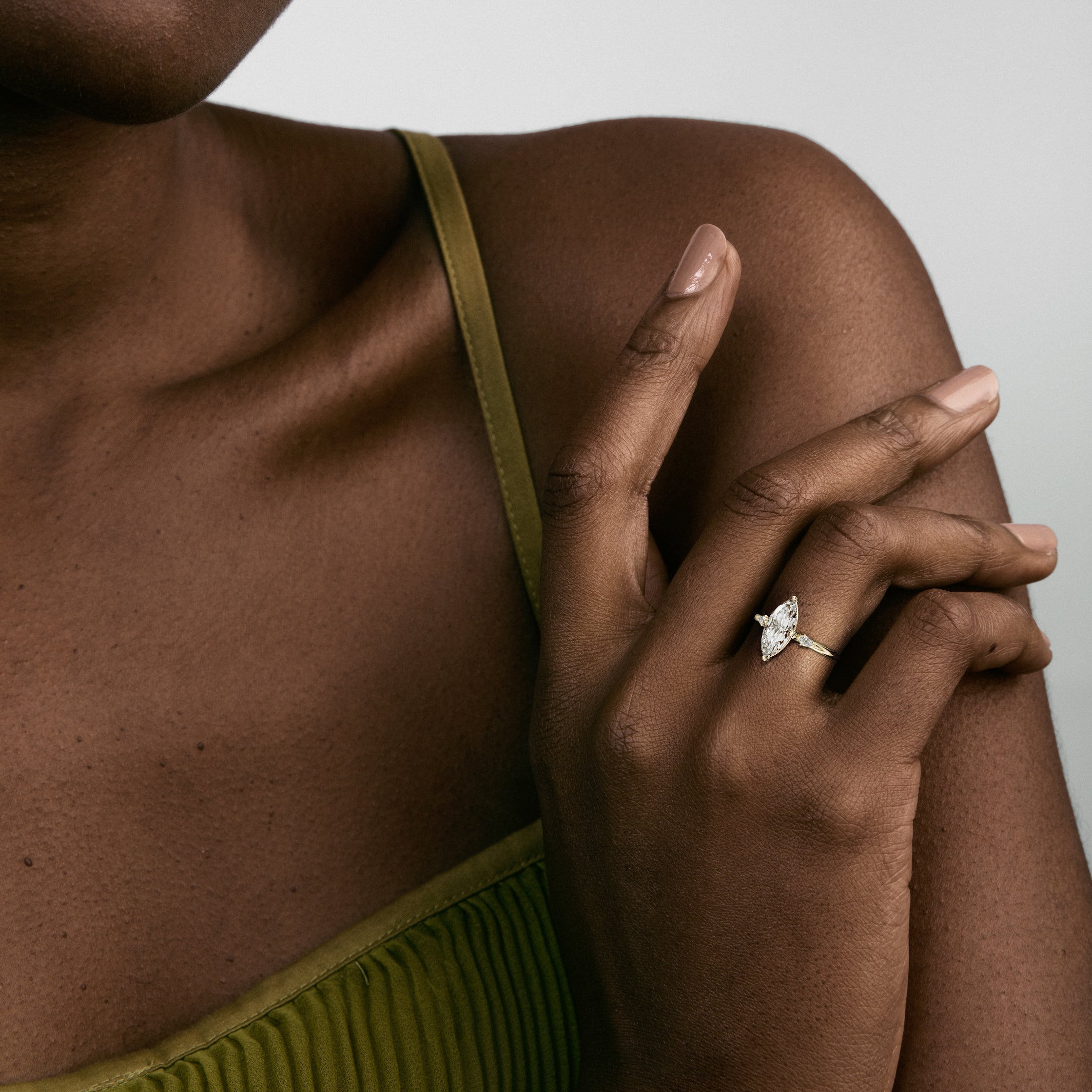 14k yellow gold three stone engagement ring with marquise diamond in compass prongs and pear accent stones worn on hand