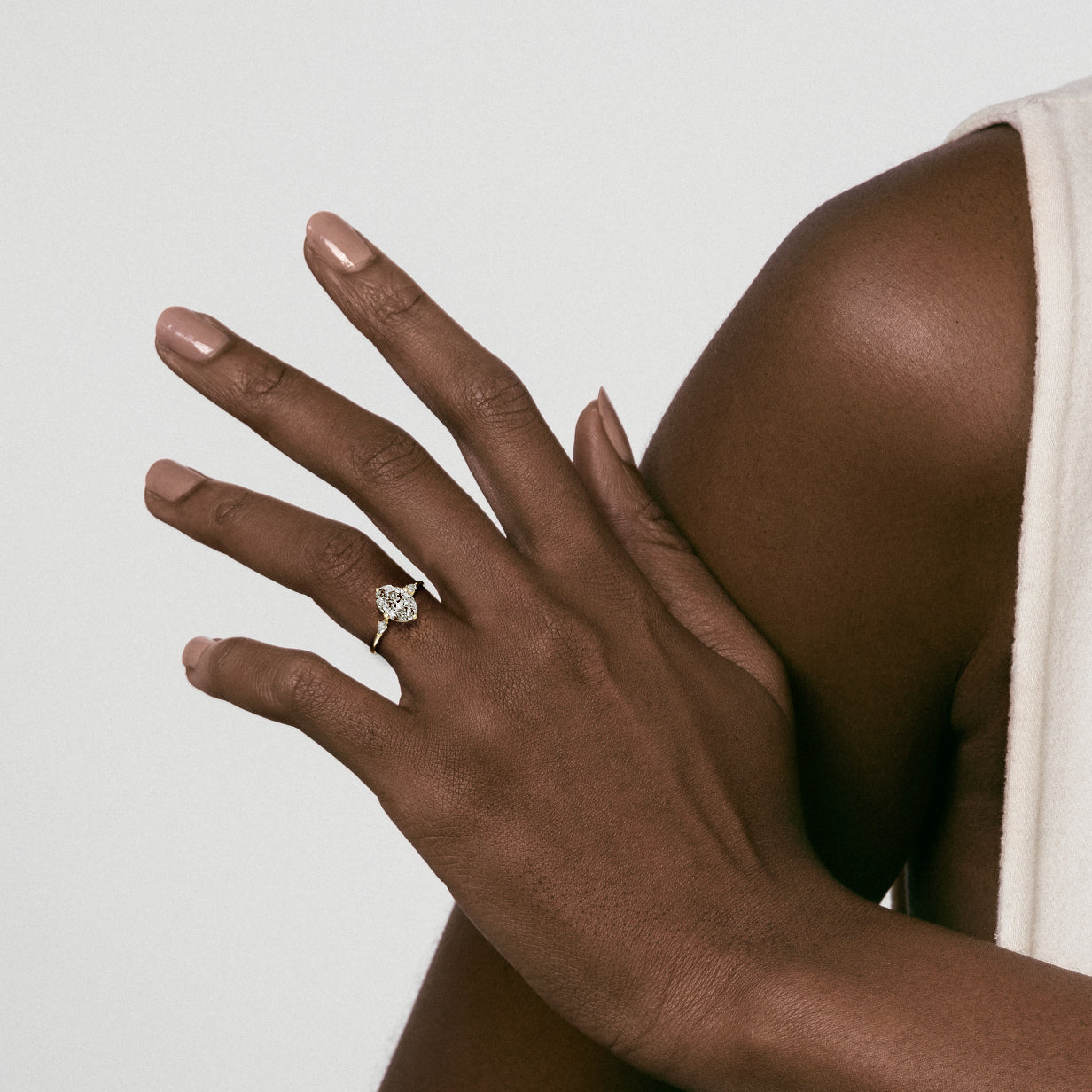 14k yellow gold three stone engagement ring with oval diamond and pear side stones worn on hand