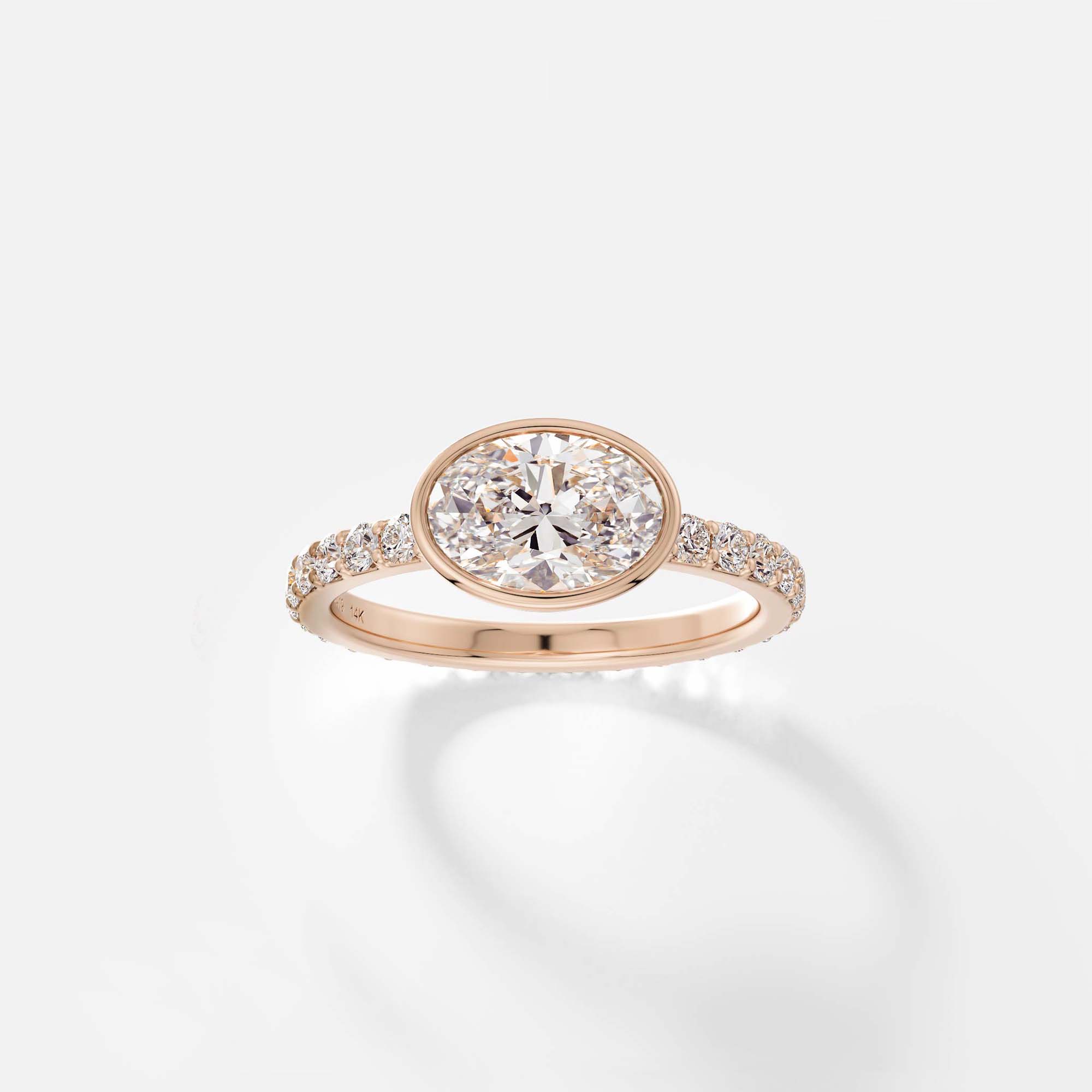 14k rose gold engagement ring with bezel set oval diamond and pavé diamond band