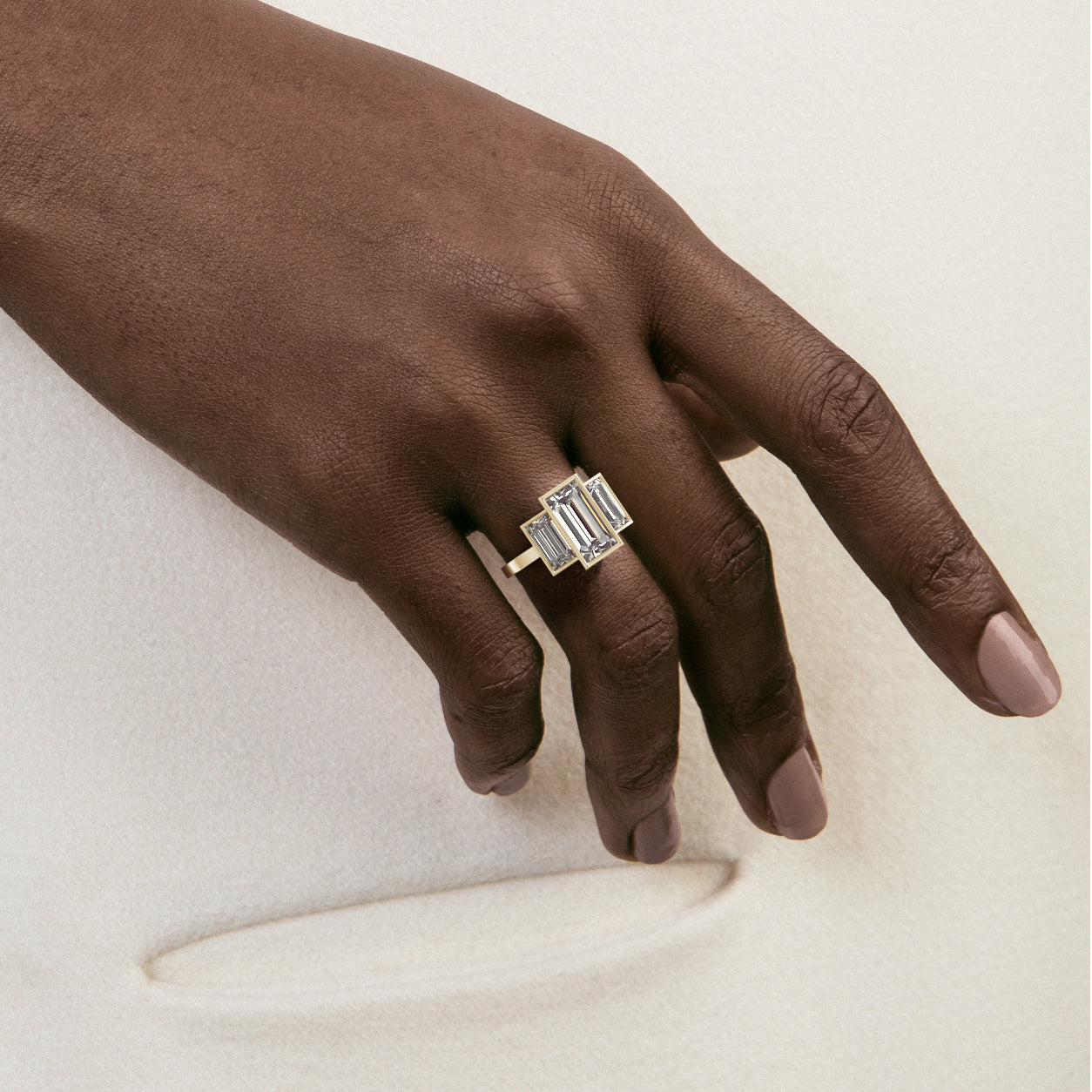 Close view of three stone engagement ring with baguette-cut center diamond and side stones on flat band