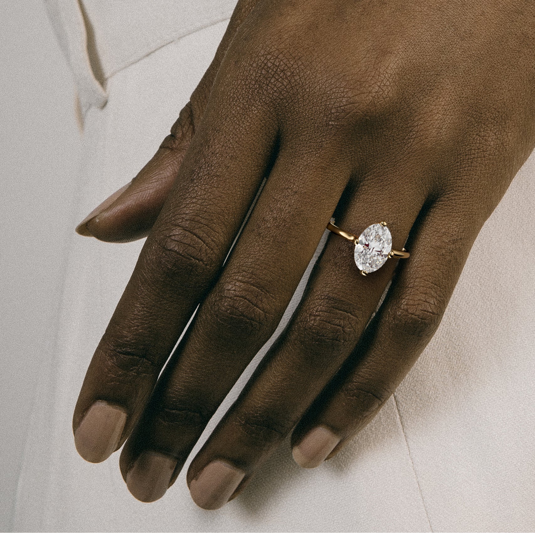 Dainty yellow gold engagement ring with oval diamond worn on hand