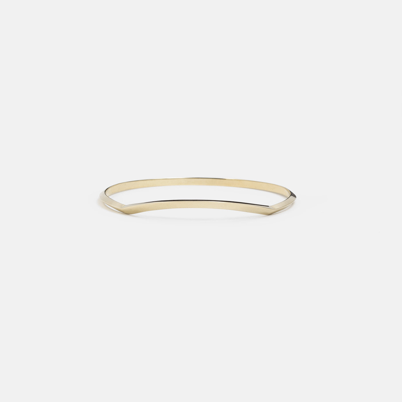 yellow brass bangle with angled tapered structure shown inverted highlighting curved design