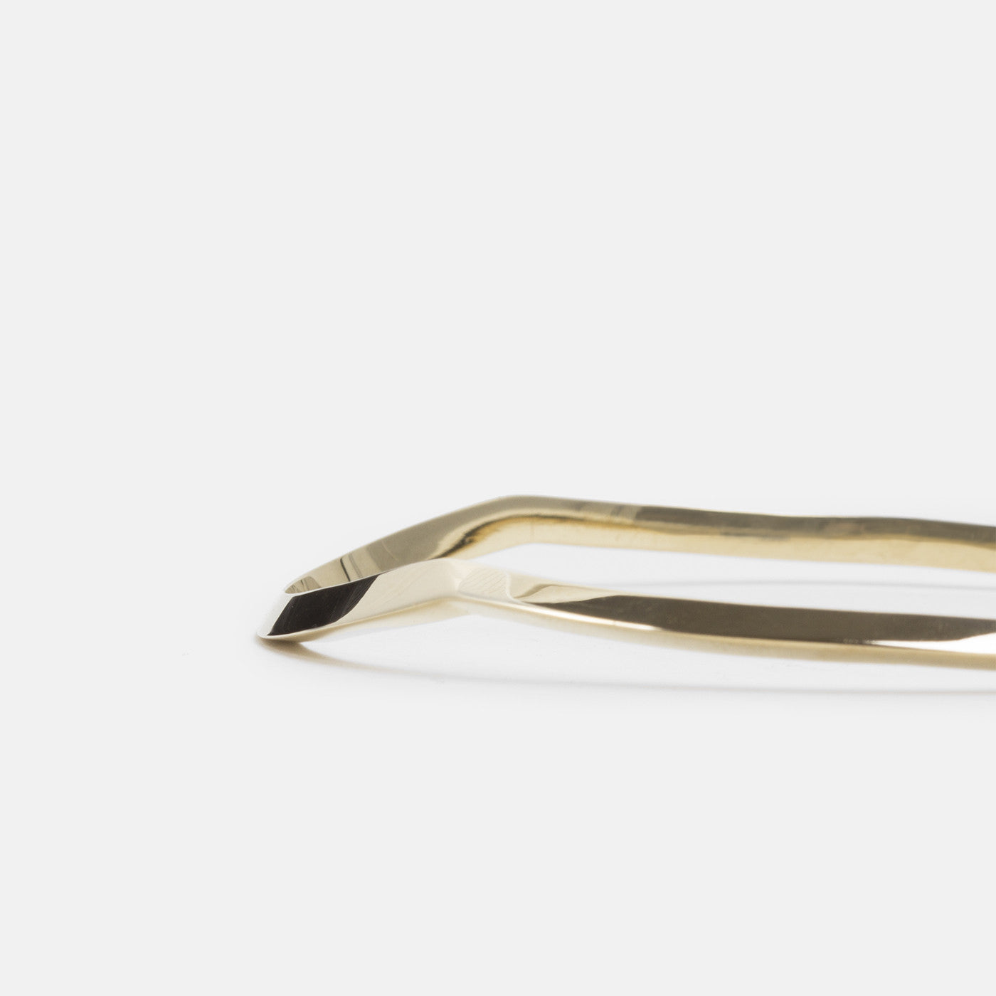 close-up of yellow brass bangle showing tapered sculptural lines and smooth polished surface