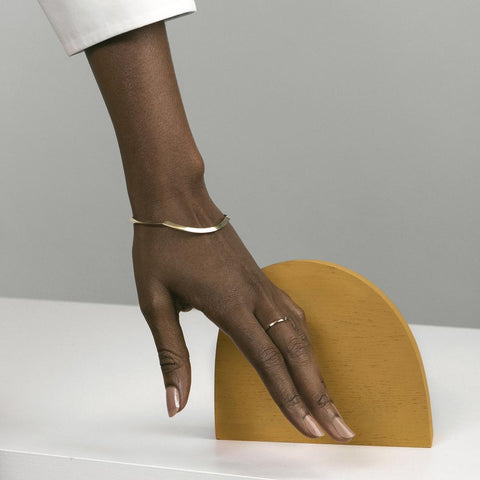 yellow brass sculptural bangle bracelet with tapered design worn on wrist in natural light
