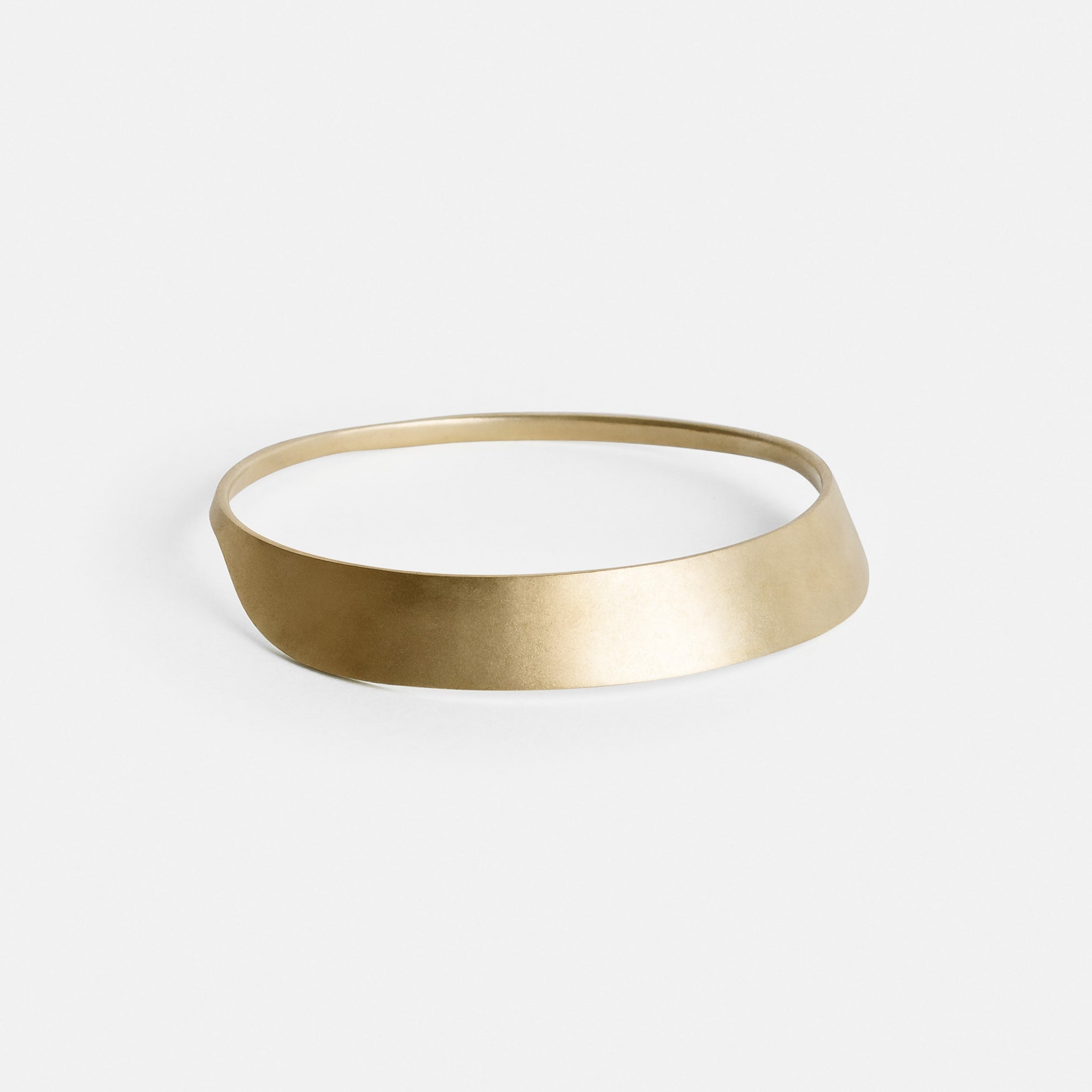 yellow brass bangle bracelet with smooth sculptural curved form shown from the front