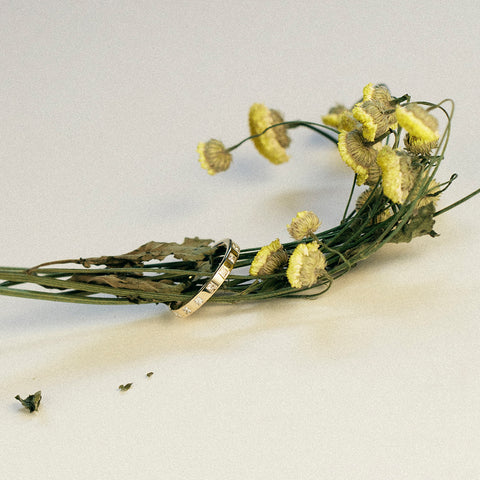 Princess-cut eternity band styled with flowers in the background