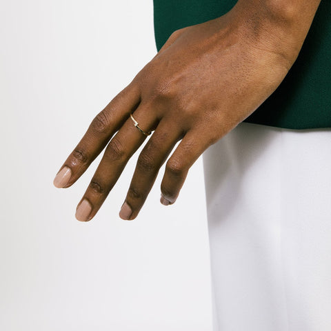 14k yellow gold thin diamond wedding band with offset vertical stones worn on hand