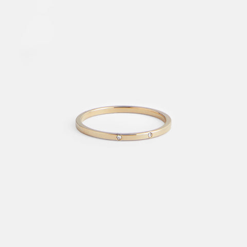 Thin flat gold wedding band with two round brilliant diamonds worn on hand