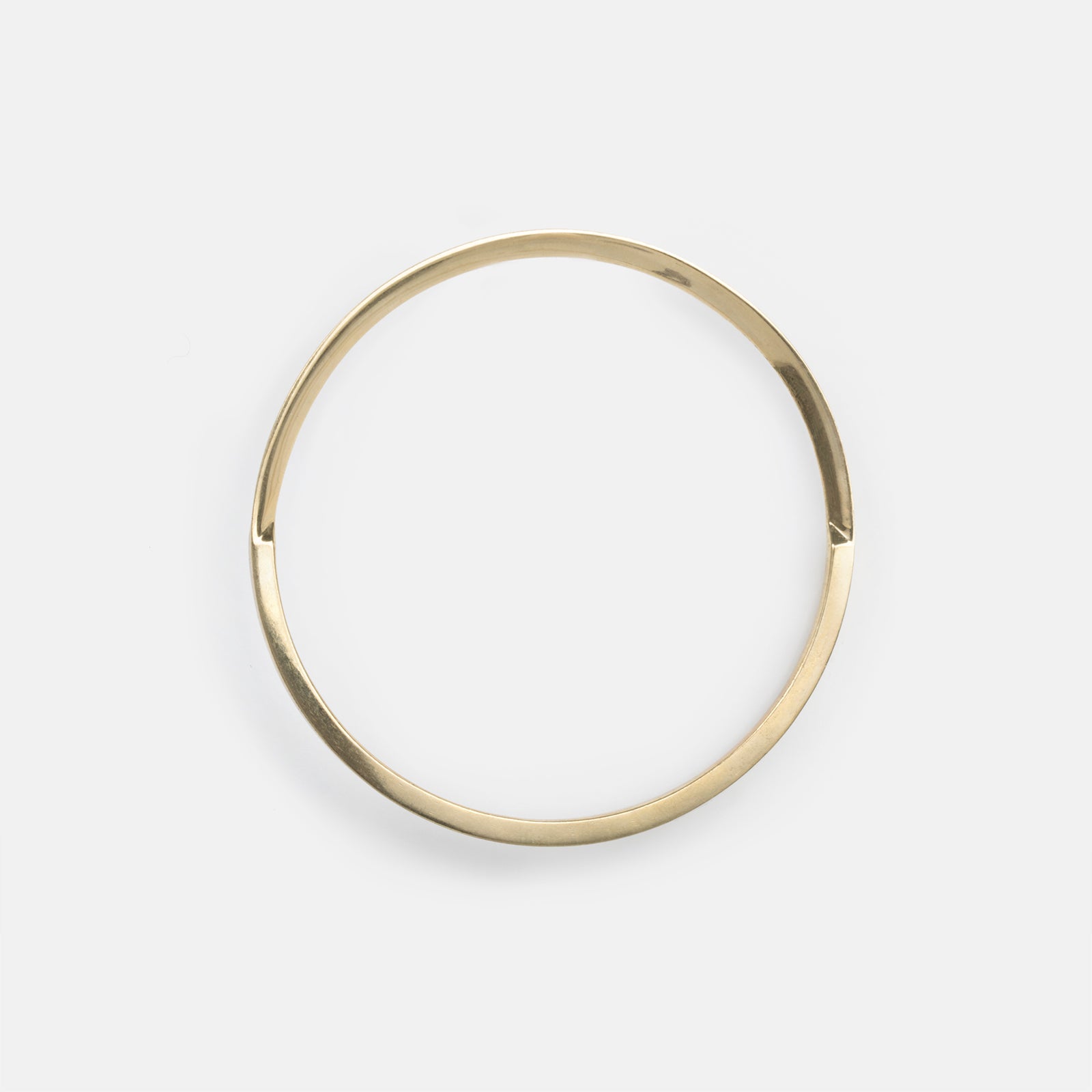 top view of yellow brass bangle bracelet showing tapered curves meeting at an angled connection